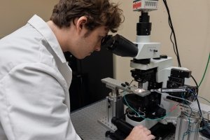 Simon Forsting is looking through a microscope, which is part of his patch-clamp rig.