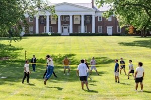 On the campus of Centre College, students play volleyball on the grass law as Old Centre can be seen in the background.