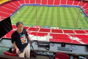 Dave Schoonaert is behind a tech table, with a view of the Kansas City FIFA World Cup Stadium.