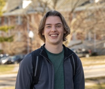 Student wearing jacket standing outside on campus