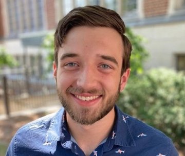Student wearing button up shirt and smiling at camera