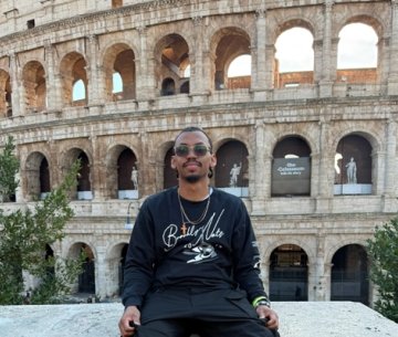 Student sitting on bench in front of the colosseum in Rome