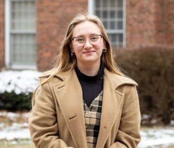 Student wearing winter coat and smiling at camera