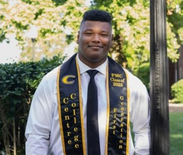 Student wearing white button up shirt and tie with graduation sash of Grissom Scholars
