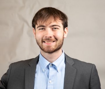 Student wearing sport coat and button up dress shirt and smiling at camera