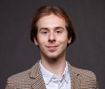 Student wearing sport coat and button up dress shirt and smiling at camera
