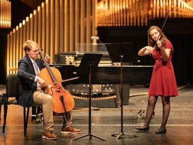 Students playing cello and violin in Newlin Hall, Norton Center for the Arts.