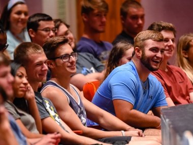 College students listening to speaker inside auditorium