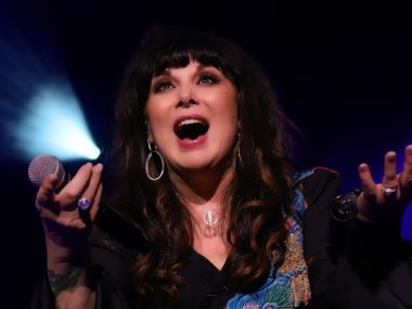 Ann Wilson holding a microphone, holding her hands out to the camera