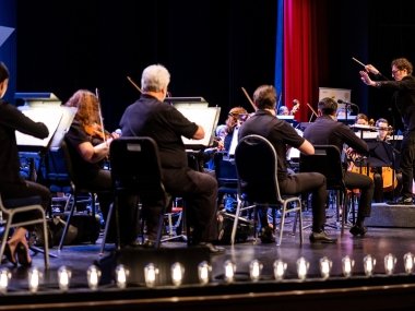 Conductor Teddy Abrams in front of an orchestra, conducting as they play