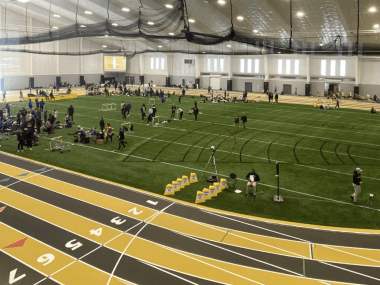 large indoor track with turf field and black and gold track wrapped around field