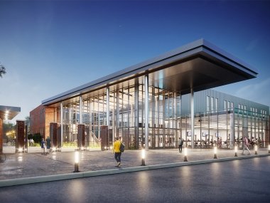 Large glass athletic building with many lights on exterior at night