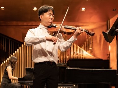 Student playing violin on stage with piano accompanist