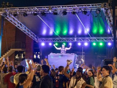 image of performer on stage with purple and green lights; audience cheering