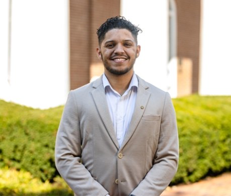 Student wearing suit coat on top of dress shirt and smiling at camera