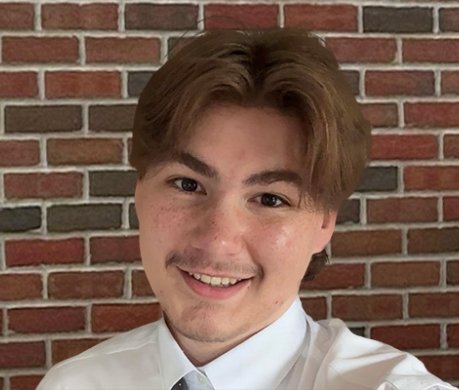 A young person in front of a brick wall