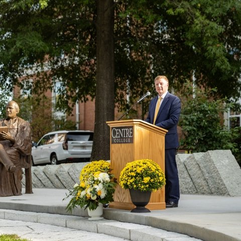 Centre President Milton Moreland at the podium next to he statue.