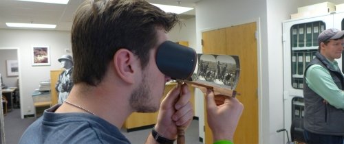 Student examining historical stereographs through a stereoscopic viewer