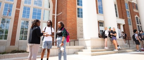 Students talking in small groups outside the library between classes