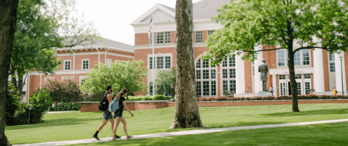 Students walking across campus in front of the Library