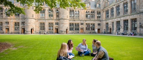 Group of Centre students sitting on lawn in Glasgow in front of historic building