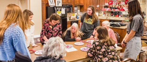 Students caring for senior citizens at assisted living home