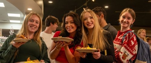 Students smiling while holding plates of food