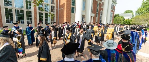 Centre graduates process between faculty lining their path in front of Grace Doherty library.