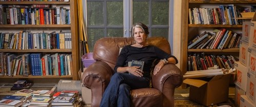 Centre College Professor of English Stacey Peebles sits in a leather armchair in a room filled with loaded book shelves and piles of books on the floor, the personal library of American author Cormac McCarthy.