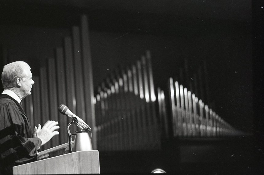 The pipes of the organ in Centre College's Norton Center for the Arts are seen in the background as Jimmy Carter speaks behind a podium.