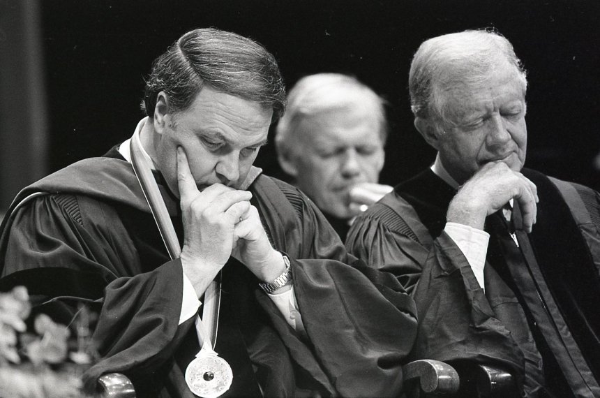 Centre College President Richard Morrill and former President Jimmy Carter, both wearing commencement regalia, bow their heads.