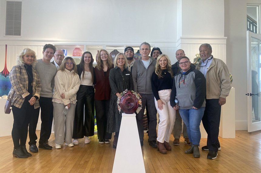 Students pose for a photo behind their contributed piece to the GLASS National Art Museum.