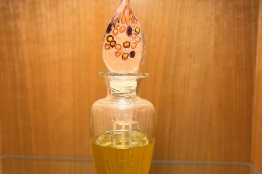 A glass bottle with an ornate glass stopper contains holy oil.