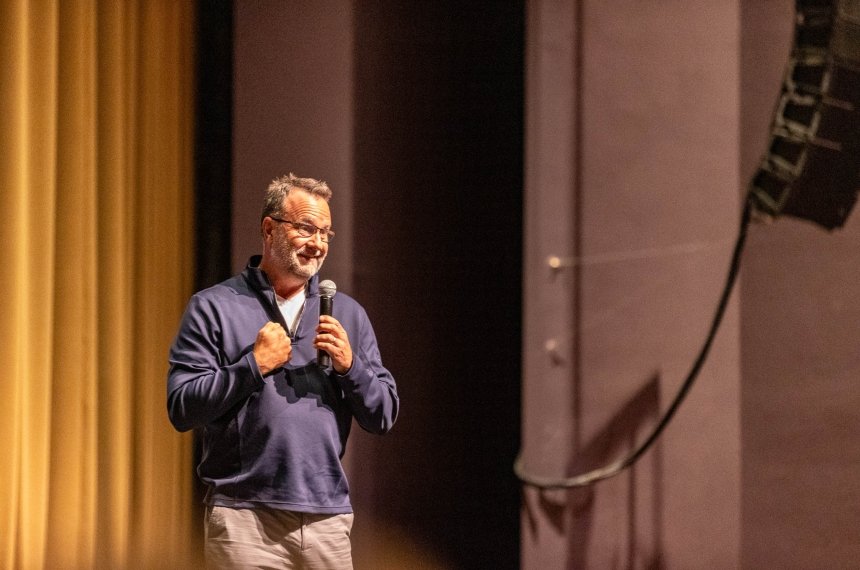 A man walks across a stage as he addresses an audience.