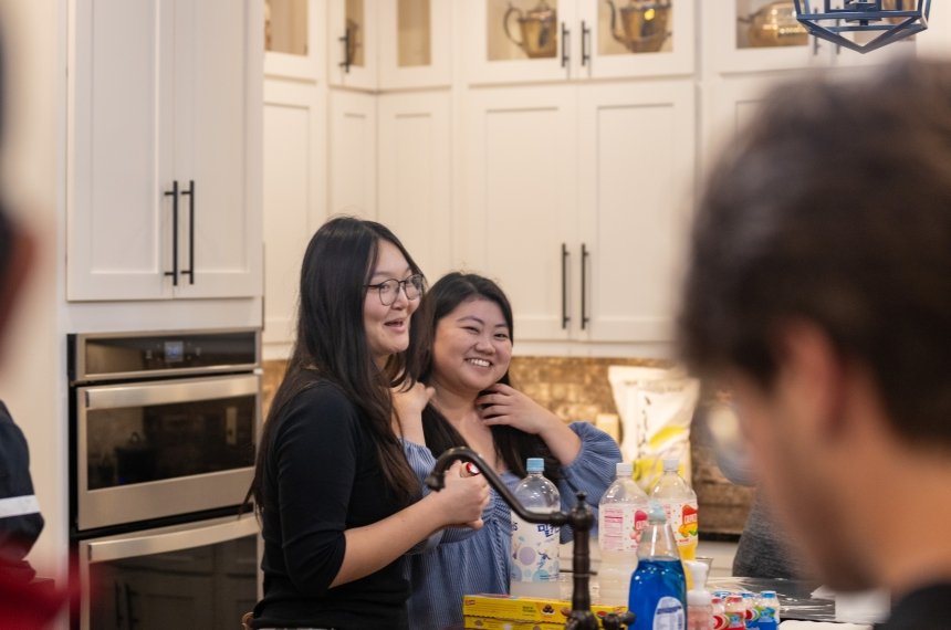 A student talks with her classmates in a kitchen.