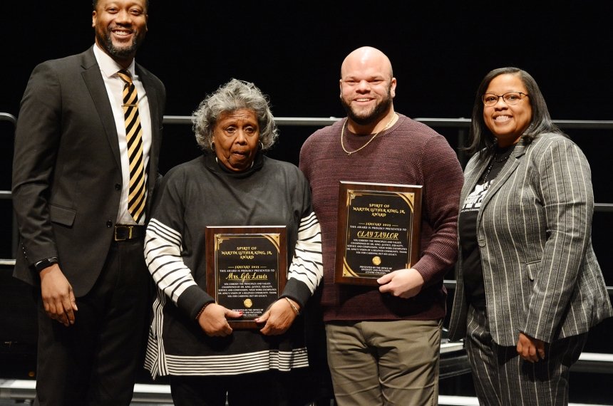 A man and woman pose with two people holding awards.