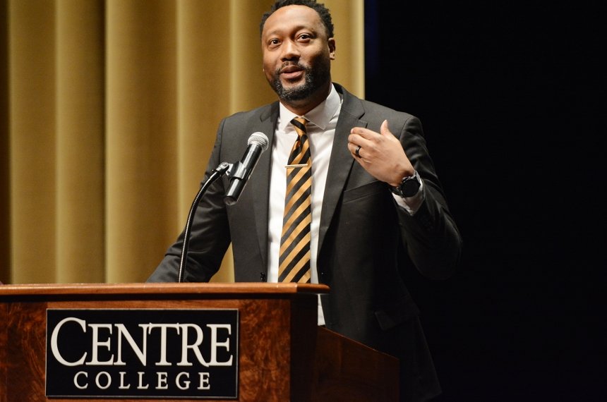 A man speaks into a microphone mounted to a lectern bearing the name Centre College.