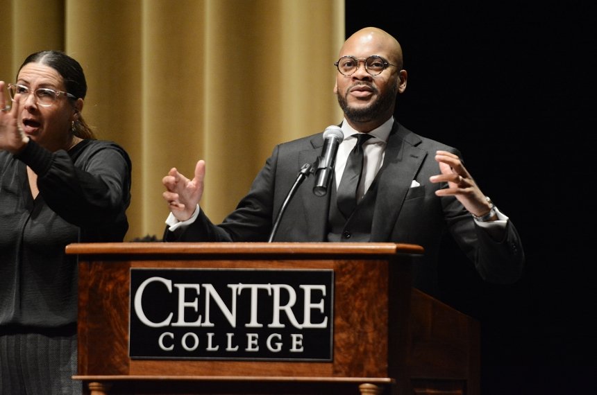 A man speaks into a microphone mounted to a lectern bearing the name Centre College.