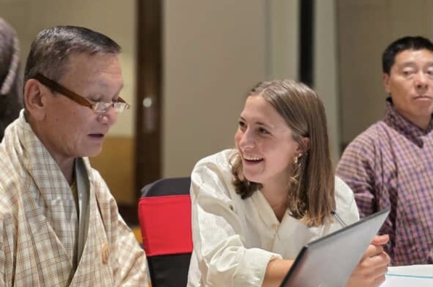 Sophia is in a workshop with others and is talking with the person next to her and laughing,