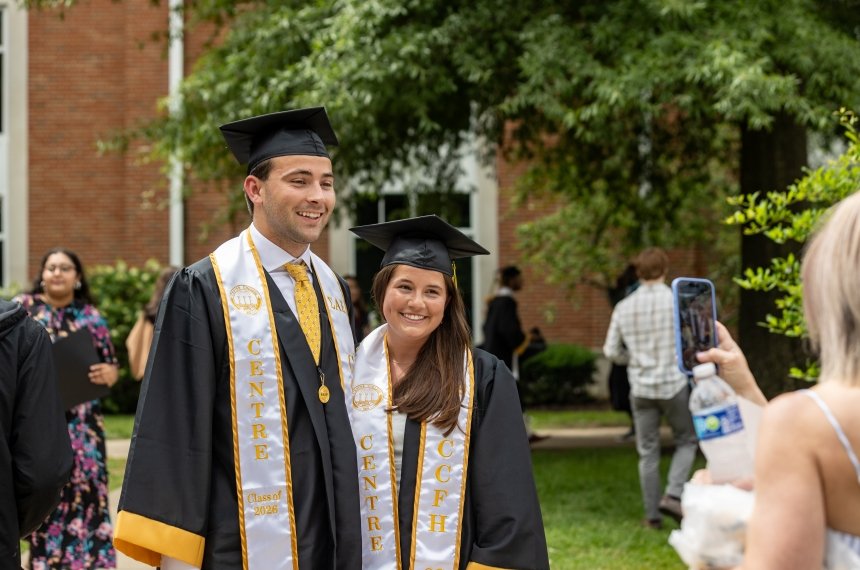 A couple pose for a photo in their graduate regalia