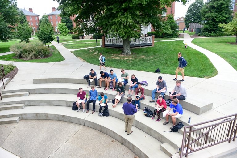 Aerial shot of students sitting on steps listening to professor lead class discussion