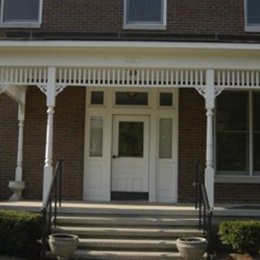 Multi level brick home with front porch with white doorway and steps leading up to porch