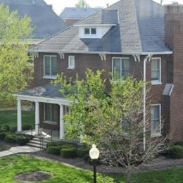 Multi level brick home with front porch with steps and sidewalk leading up to house