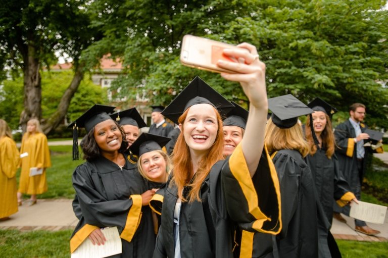 multiple students leaning in for a selfie photo in graduation attire