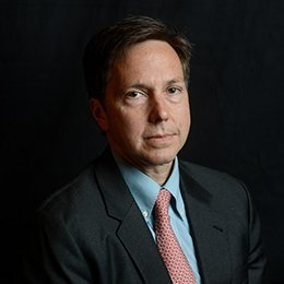 Person wearing suit standing in front of dark wall