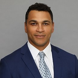 Person wearing navy suit in front of grey background
