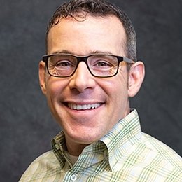 Person wearing glasses and green shirt smiling