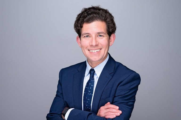 A photo of man in a suit with arms crossed