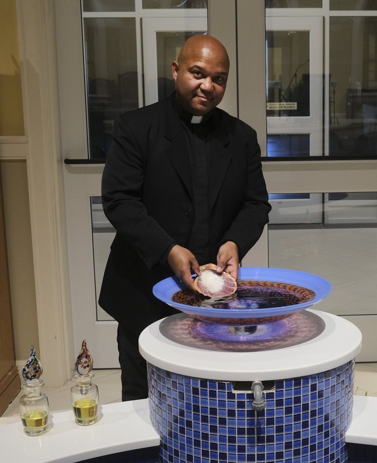 A man in a black priest's clothing poses for a photo.