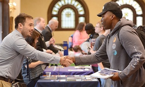 student participating in law school fair on campus shaking hands with recruiter